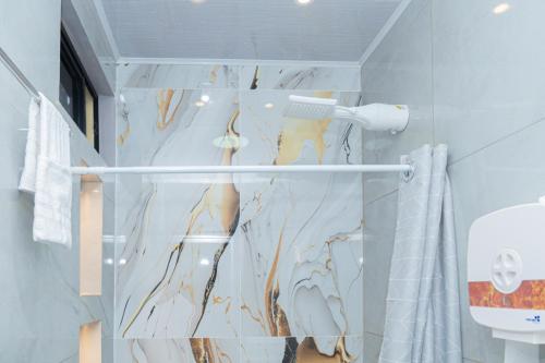 ein Badezimmer mit Duschvorhang und Marmorwand in der Unterkunft Deramai in Santo Domingo de los Colorados