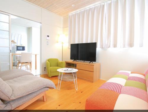 a living room with a television and a couch at 天草まちなかアパートメントホテルMoi!Moi!