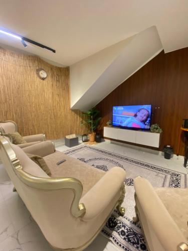 Una sala de estar con sillas y un televisor de pantalla plana. en Jasmine Corner Chalet, en Mawāliḩ