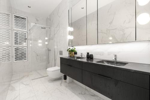 a white bathroom with a sink and a toilet at Unbeatable Central Location - Reykjavíks Most Exclusive Luxury Apartments in Reykjavík