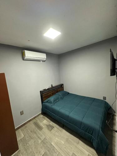 a bedroom with a bed with a green comforter at Depa nuevo y equipado en Saltillo 2 recámaras in Saltillo