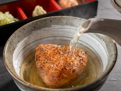 a pot filled with sauce with a piece of meat at Izumigo AMBIENT Azumino Hotel in Azumino