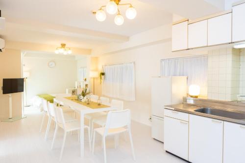 a kitchen with white cabinets and a table and chairs at Miraie Katano Stay in Kisabe