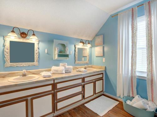 uma casa de banho azul com um lavatório e um espelho em Barefoot Children em Tybee Island