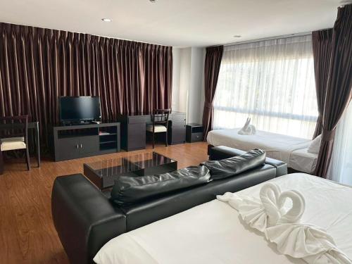 a hotel room with a couch and a tv at Golden Good Hill Hotel, Chiang Mai in Chiang Mai