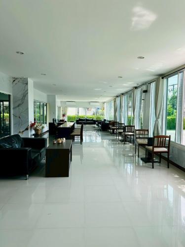 a living room with couches and tables and windows at Golden Good Hill Hotel, Chiang Mai in Chiang Mai