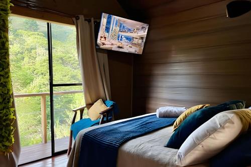 a bedroom with a bed and a large window at Chalés Duquesa do Vale in Campos do Jordão