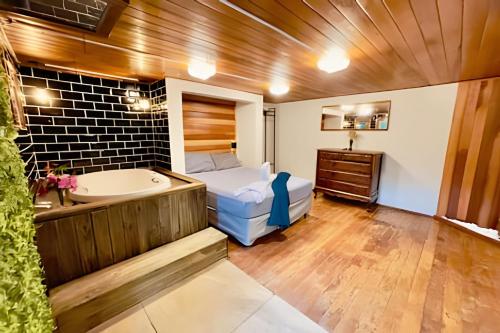 a bathroom with a tub and a bed and a bath tub at Chalés Duquesa do Vale in Campos do Jordão