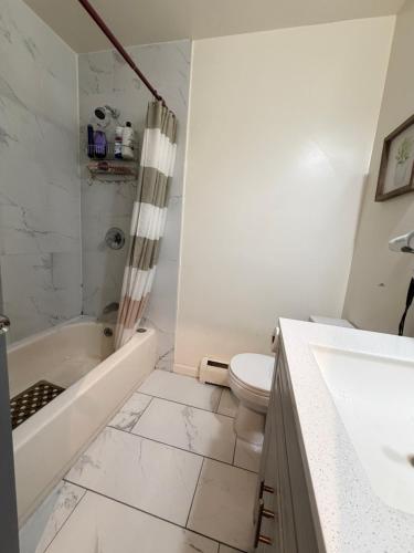 a white bathroom with a tub and a toilet at A sweet home-Room D in Woodside