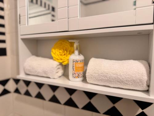 een badkamerplankje met handdoeken en een fles schoonmaakmiddel bij Cozy Nest in Grays Thurrock