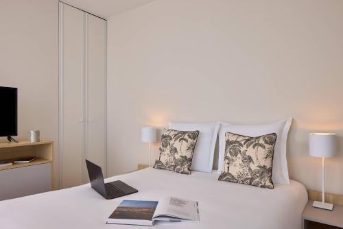 a bedroom with a white bed with a laptop on it at Zenitude Hôtel-Résidences Bordeaux Saint-Jean in Bordeaux