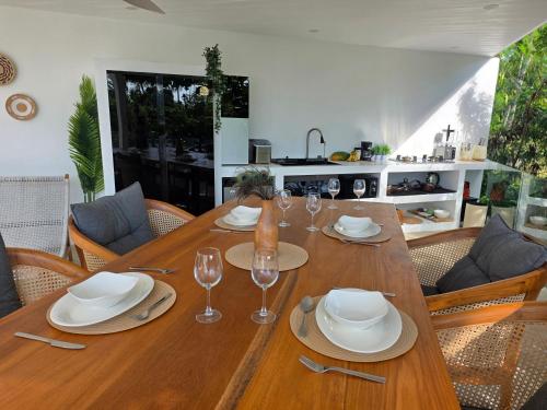 a wooden table with plates and wine glasses on it at Luxury manao poolvilla with seaview Koh Lanta in Ko Lanta