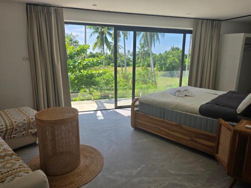 a bedroom with a bed and a large window at Luxury manao poolvilla with seaview Koh Lanta in Ko Lanta
