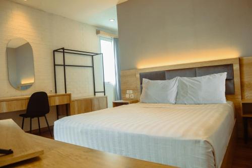 a bedroom with a bed with a desk and a mirror at Twin Tower Hotel & Residence in Surabaya