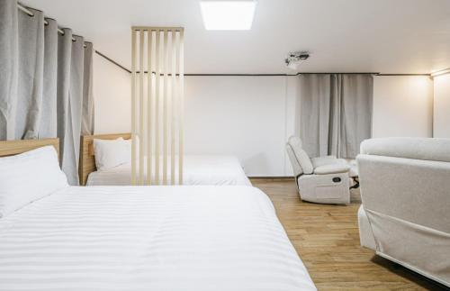 a hotel room with two beds and a chair at The Oakra Hotel in Jeju