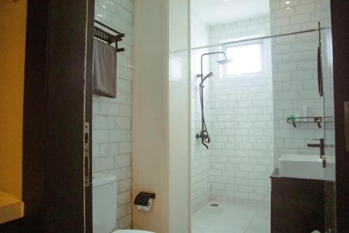 a bathroom with a shower and a toilet and a sink at Twin Tower Hotel & Residence in Surabaya