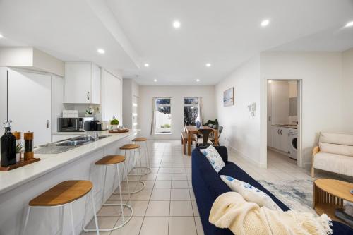 a kitchen and living room with white cabinets and blue chairs at Aldinga Horizon in Aldinga Beach