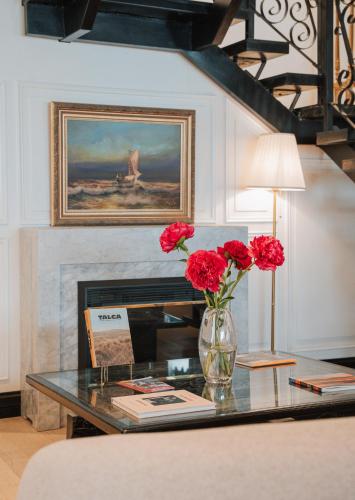 a table with a vase with red flowers on it at Hotel Marcos Gamero in Talca