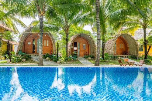 un complexe avec piscine et palmiers dans l'établissement Hoianam Village, à Thăng Bình