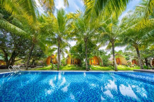 einen Pool mit Palmen vor einem Haus in der Unterkunft Hoianam Village in Thăng Bình