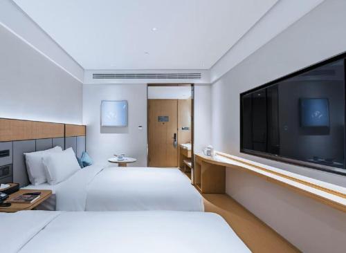 ein Hotelzimmer mit zwei Betten und einem Flachbildfernseher in der Unterkunft JI Hotel Shanghai Meiling North Road Subway Station in Shanghai