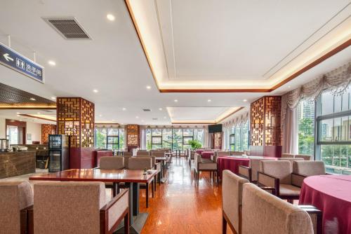 a dining room with tables and chairs and windows at 青岛机场富华酒店 in Qingdao