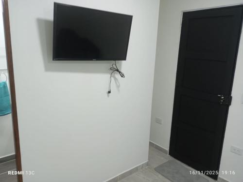 uma televisão de ecrã plano numa parede ao lado de uma porta em Alojamientos Jamar em Rionegro