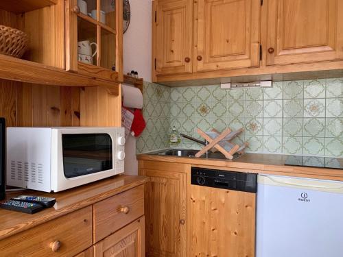 eine Küche mit Holzschränken und einer weißen Mikrowelle in der Unterkunft Studio-Cabine au Praz de Lys, 4 pers, proche pistes - FR-1-815-30 in Le Praz de Lys