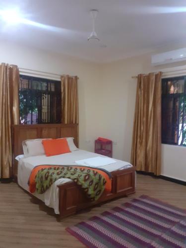 a bedroom with a bed in a room with windows at Faith Under Fire Villa in Migogoni