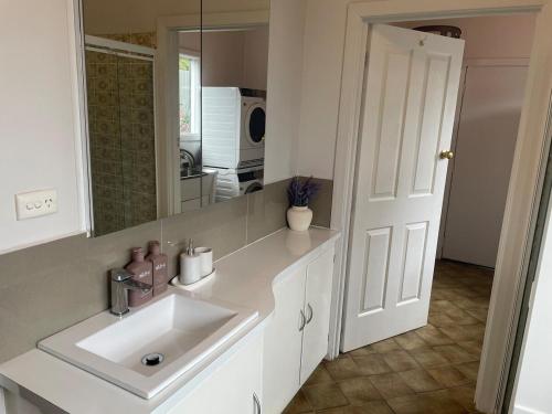 une salle de bain blanche avec un lavabo et un miroir dans l'établissement Clonburn Manor at Sovereign Hill, à Ballarat