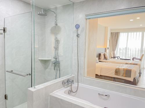 ein Bad mit einer Dusche, einem Bett und einem Spiegel in der Unterkunft Uniland Golf & Resort in Nakhon Pathom