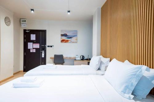 a bedroom with two white beds and a desk at Infinite Hotel-Ratchada in Bangkok