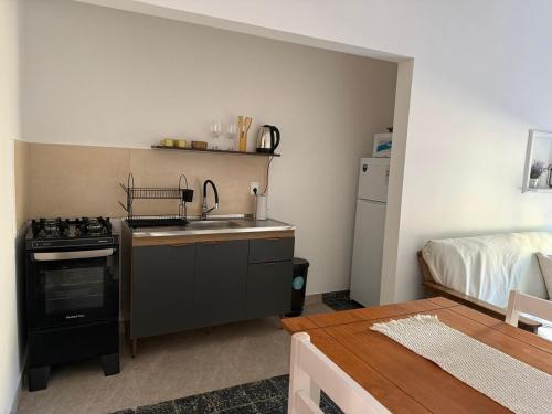 a kitchen with a sink and a stove and a bed at Casa en el centro de Carmelo in Carmelo