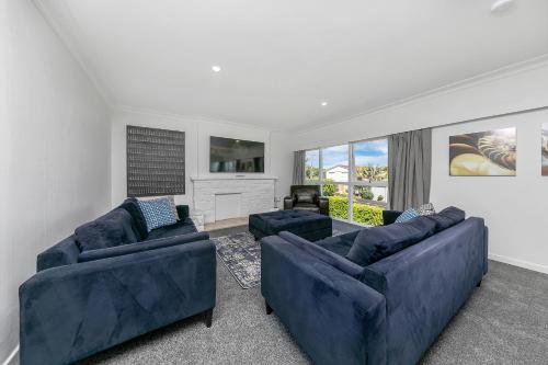 a living room with two blue couches and a tv at Spacious house 5 minutes walk to St Helier Beach in Auckland