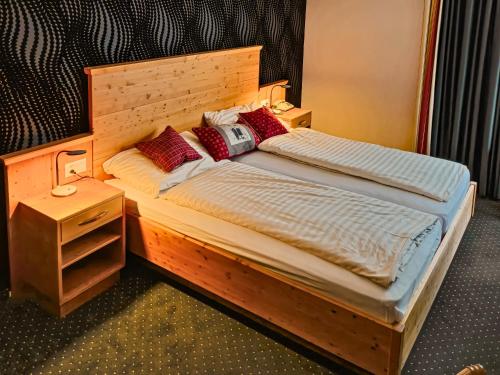a bed with a wooden headboard and a night stand at Hotel Nolda in St. Moritz