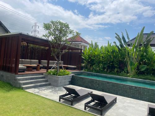 a swimming pool with two chairs next to a house at Medewi Surf Villa Luxury in Airsatang