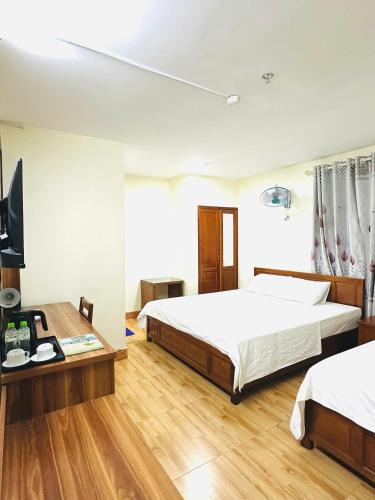 a bedroom with two beds and a desk and a tv at Oriio Hotel Cát Bà in Cat Ba