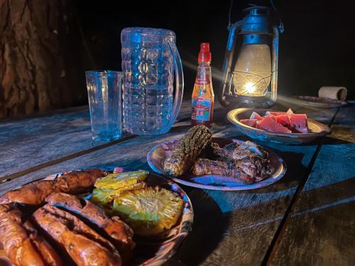 Belihuloya Fattah Camping Resort في بيلهول اويا: طاولة خشبية عليها أطباق طعام