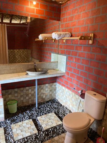 baño con aseo y pared de ladrillo en Villa Lumbung Ayu Sari & Spa, en Karangasem
