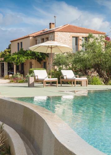 einen Pool mit zwei Stühlen und einem Sonnenschirm neben einem Haus in der Unterkunft Vrysomylos in Vromonérion