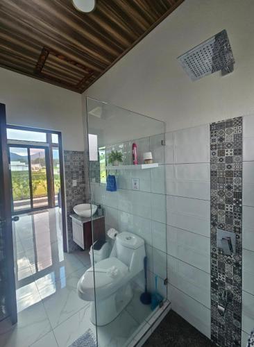 a bathroom with a toilet and a glass shower at Casa Tigrillo - La Fortuna in Agua Azul