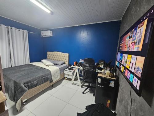 ein Schlafzimmer mit einem Bett, einem Schreibtisch und einem Fernseher in der Unterkunft Quarto com ar Perto Furg,Praia! in Rio Grande