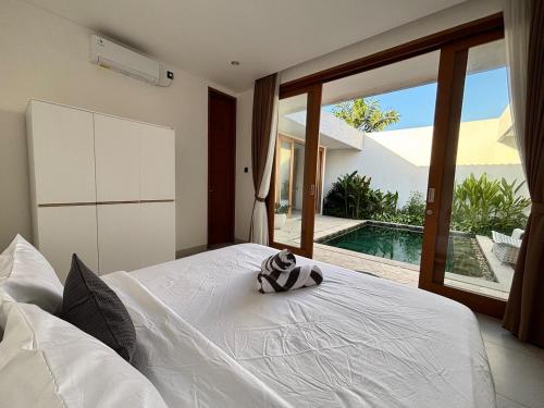 a bedroom with a white bed with a view of a pool at Casa Gemellia Brand New 2BR in Umalas in Kerobokan