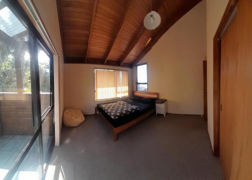 Un dormitorio con una cama en una habitación con ventana. en cliff top house guest rooms, en Whangaparaoa