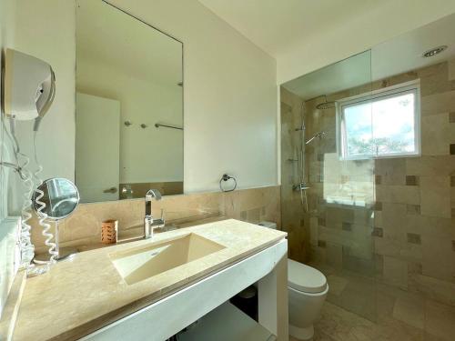 une salle de bain avec un lavabo, des toilettes et un miroir dans l'établissement Playa Bonita Modern Beachfront Penthouse Retreat, à La Ceiba
