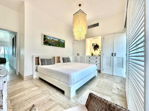 - une chambre avec un grand lit blanc et un lustre dans l'établissement Playa Bonita Modern Beachfront Penthouse Retreat, à La Ceiba