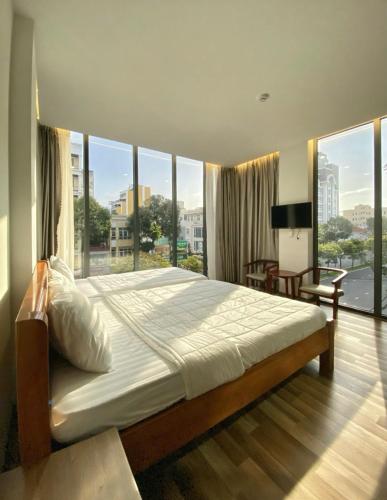 a bedroom with a large bed and large windows at M Bee Hotel in Can Tho