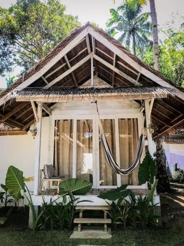 une maison blanche avec un hamac devant dans l'établissement Verde Bungalows Siargao, à General Luna