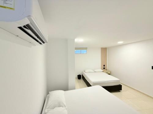 a white room with two beds in it at The Host apartamentos At Los Angeles in Santa Marta
