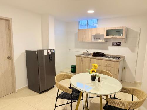 a small kitchen with a table and a refrigerator at The Host apartamentos At Los Angeles in Santa Marta